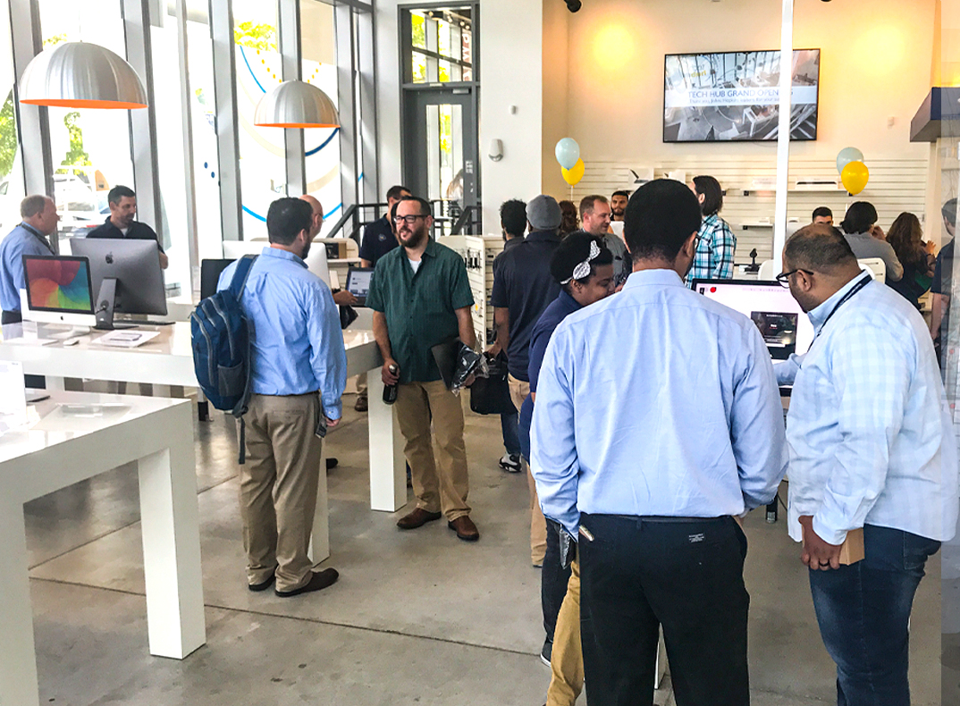 Groups of people gathering around tables of technology during the Tech Hub grand opneing